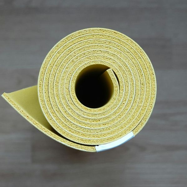 Roll of grey yoga mat on dark wooden floor