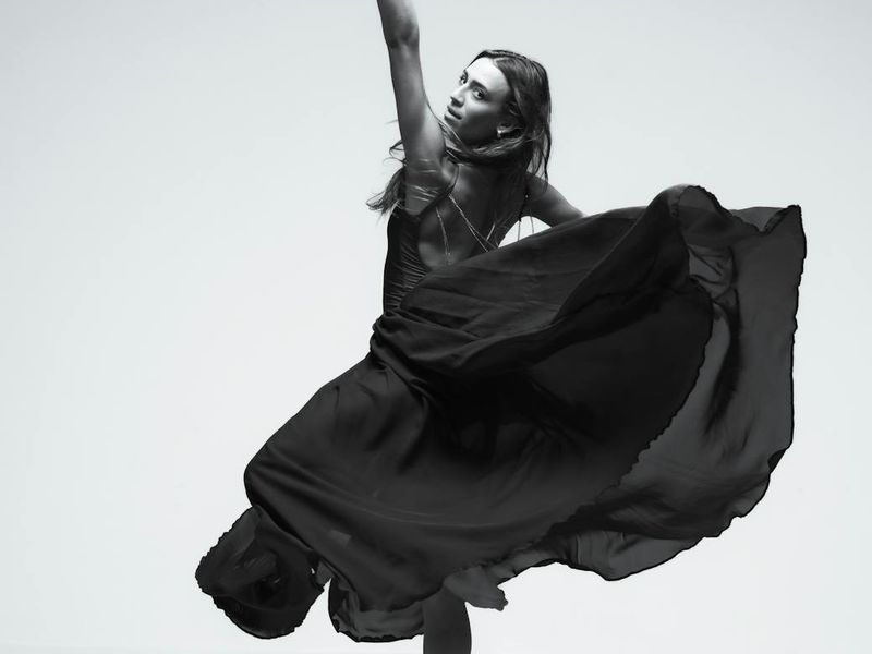 Woman performing elegant fluid movements in dark studio